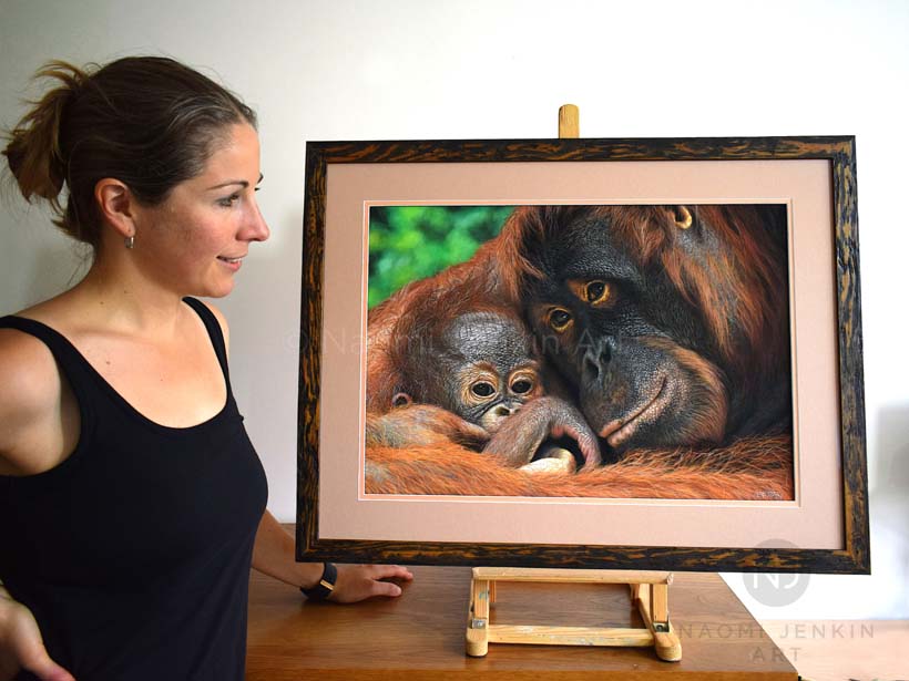 Wildlife artist Naomi Jenkin with framed orangutan painting. 