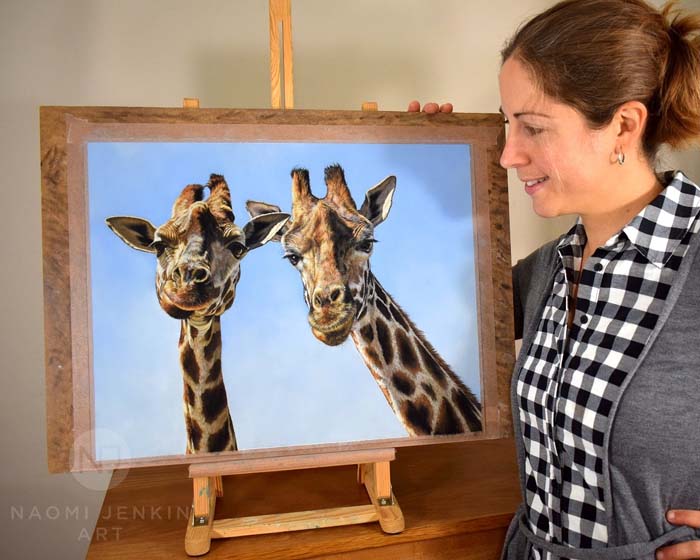 Wildlife artist Naomi Jenkin with portrait of two giraffes. 